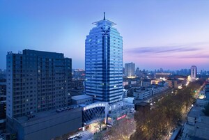 Un edificio de gran altura con un diseño moderno, rodeado de otros edificios y una calle concurrida.