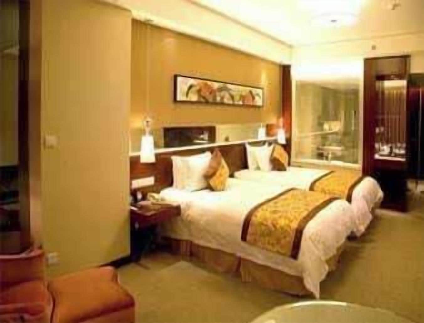 A hotel room with two beds, a nightstand, a lamp, and a painting on the wall.