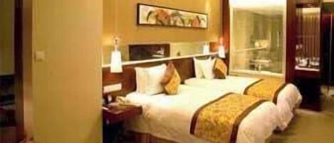 A hotel room with two beds, a nightstand, a lamp, and a painting on the wall.