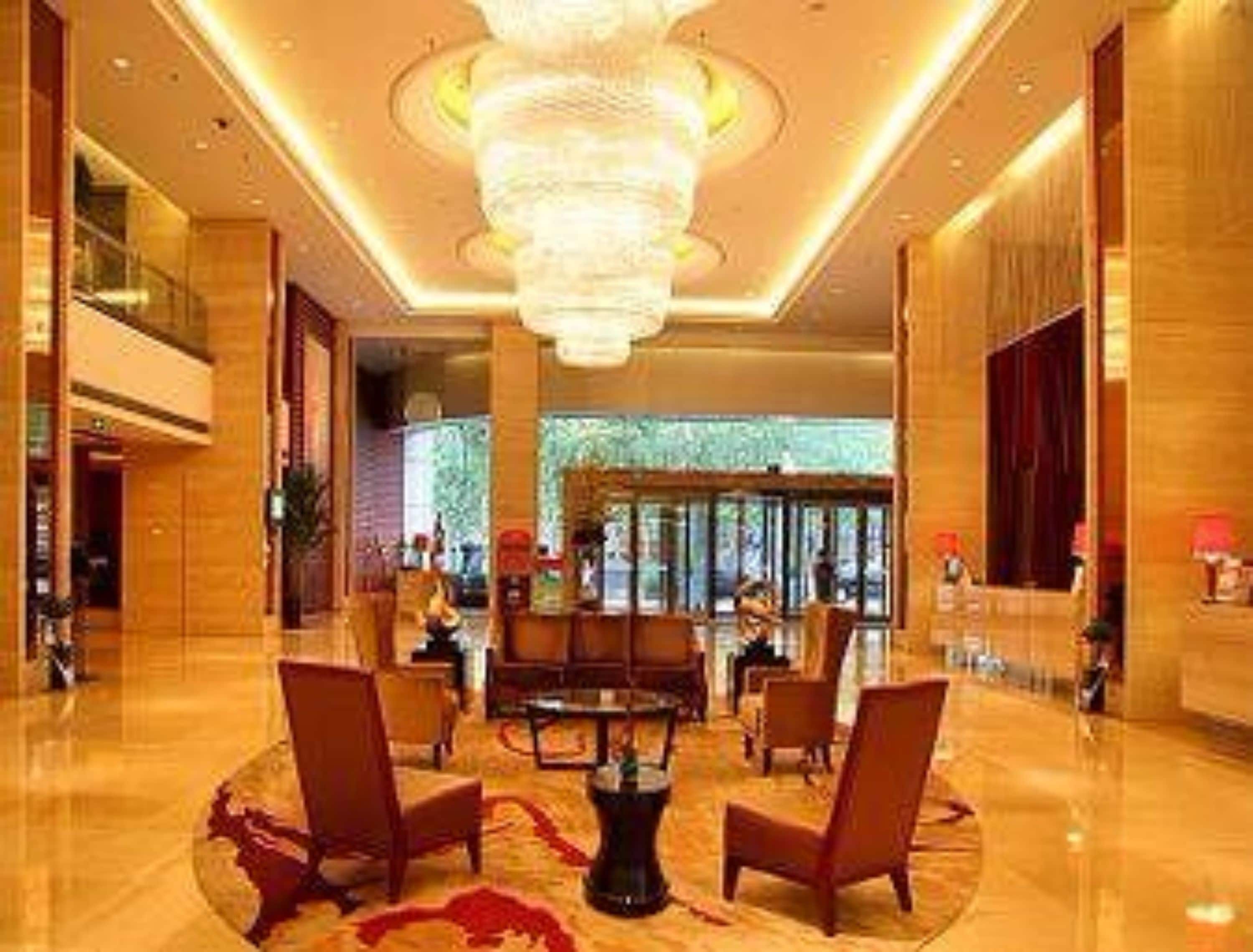 A spacious lobby with a grand chandelier, comfortable seating, and a reception desk.