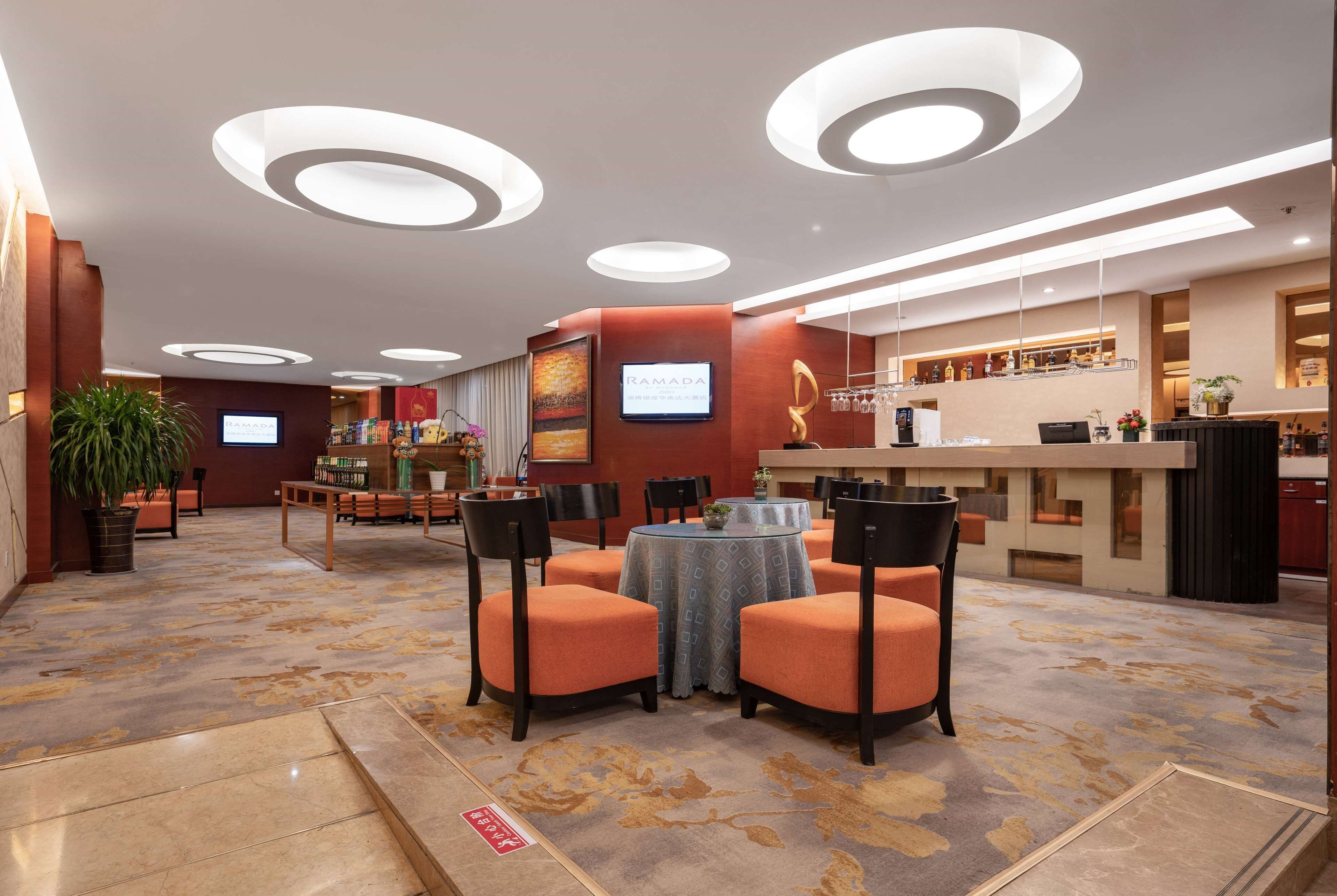 A hotel lobby with a reception desk, seating area, and a bar.
