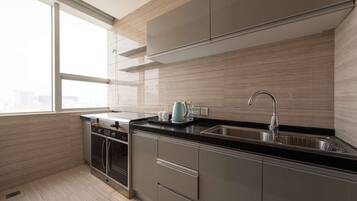 A modern kitchen with stainless steel appliances, a black countertop, and a window providing natural light.