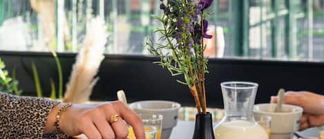 Una mesa con una cesta de pasteles, un florero con flores y una jarrón de leche.