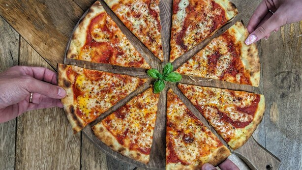 Una pizza con ocho porciones sobre una tabla de madera.