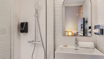 Een moderne badkamer met een douchecabine van glas, een wit wastafelmeubel en een blauwe badkamerkast.