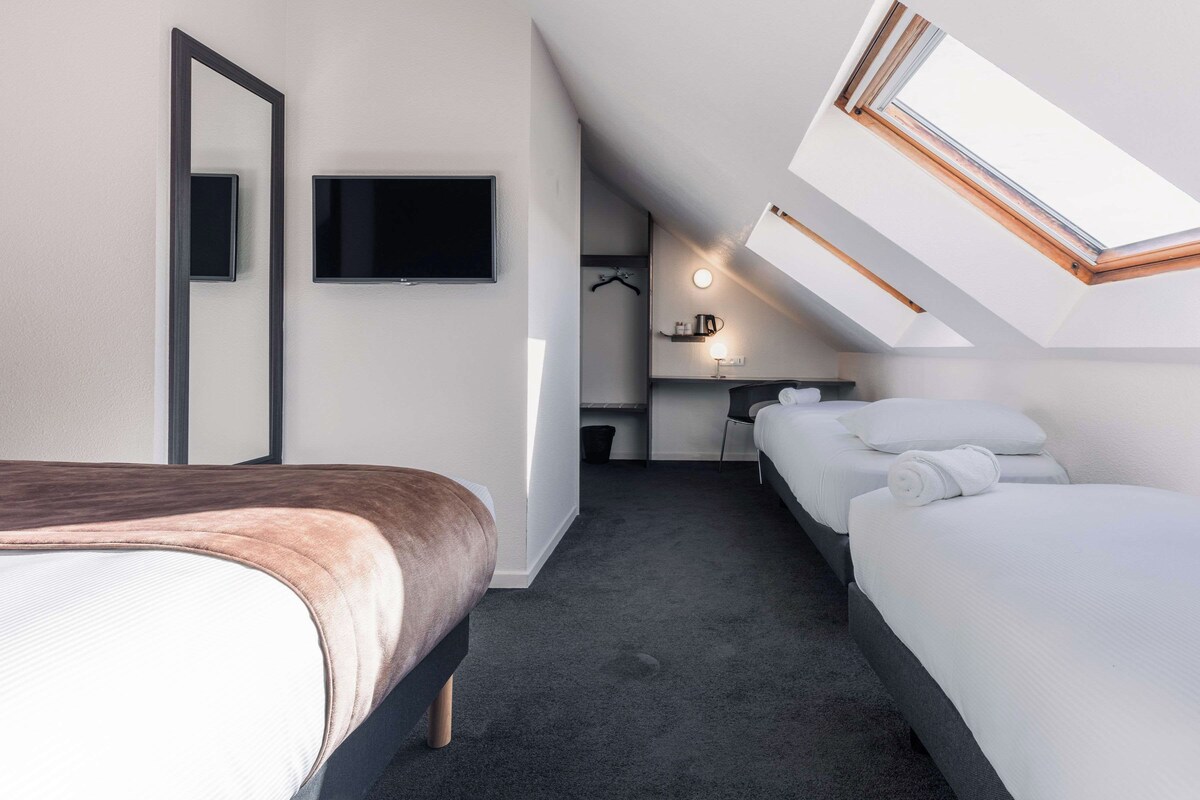 Habitació d'hotel amb un llit, escriptori, cadira i televisió.