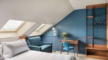 Une chambre moderne avec une lucarne, un bureau, une chaise et une armoire.