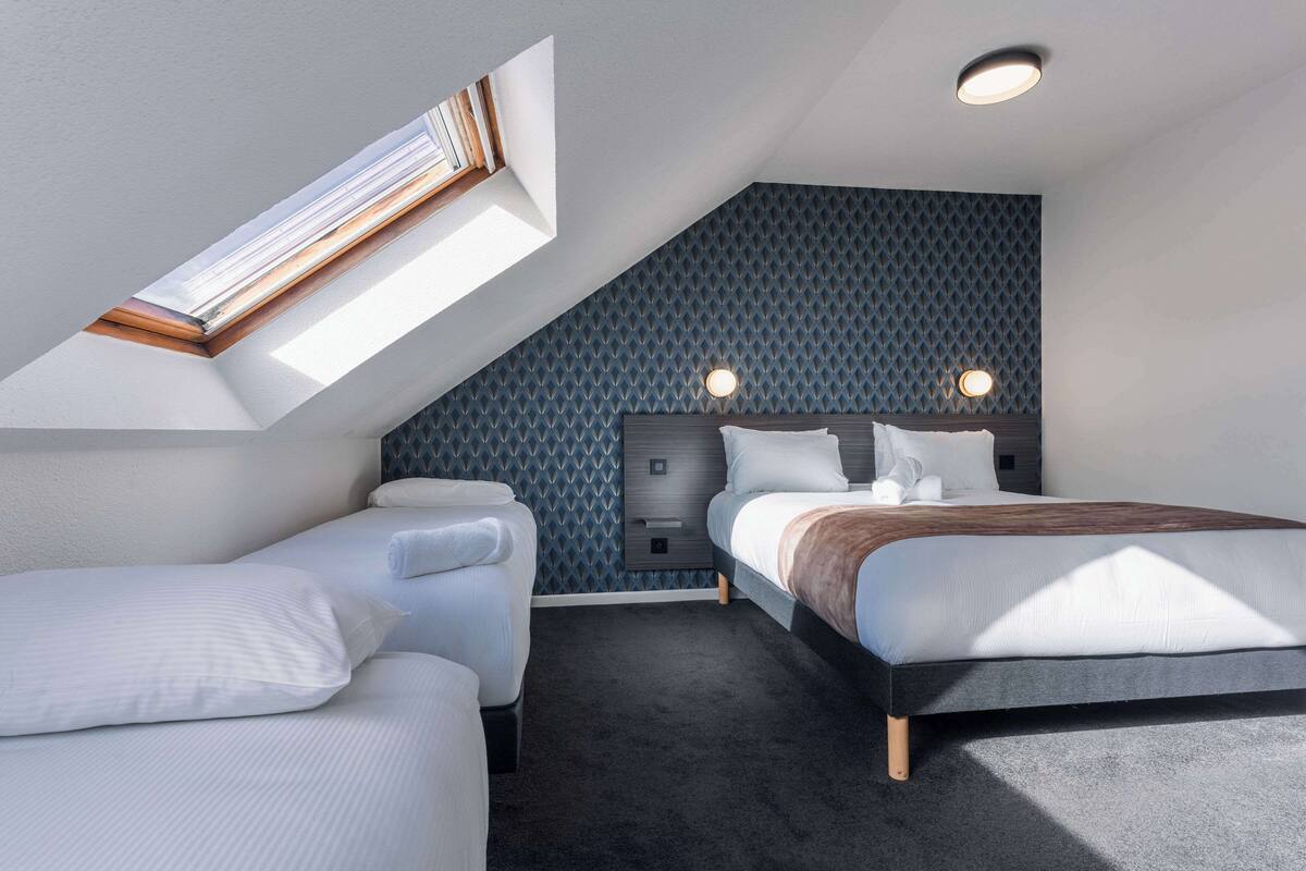 Een moderne slaapkamer met dakraam, een bed met hoofdeinde, een nachtkastje en een muur met een geometrisch patroon.