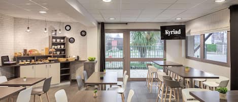 Un restaurante moderno con pared de ladrillo, techo blanco y un letrero que dice "Kyriad".