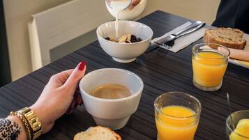 A breakfast setting with a bowl of cereal, toast, a kiwi slice, and a plate with jam and toast.