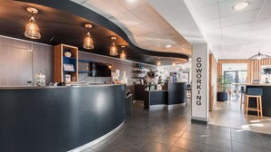 Een moderne co-workingruimte met een gebogen receptiebalie, hanglampen en een goed zichtbaar 'Coworking' bord.
