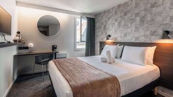 Habitación de hotel con cama, escritorio, silla y un espejo grande.