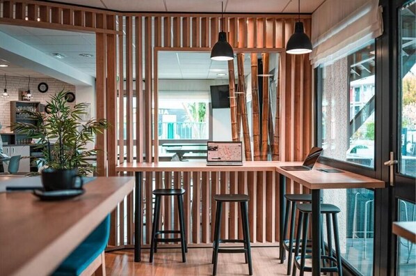 A modern cafe with wooden slats, bar stools, and pendant lighting. - Kyriad Saint Brieuc - Tregueux (Tregueux)