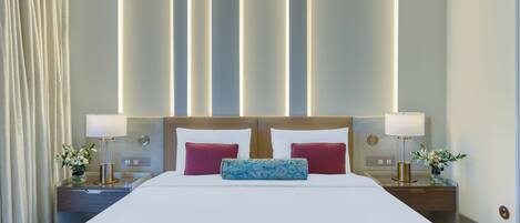 Habitación de hotel con una cama grande, dos mesitas de noche con lámparas y una pared con paneles de luz verticales.