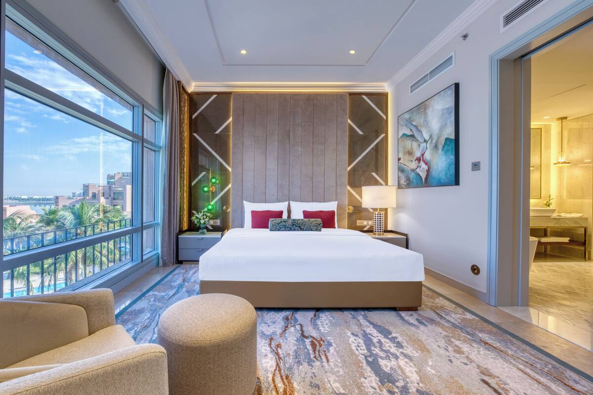 A modern hotel room with a large bed, a view of the city, and a balcony.
