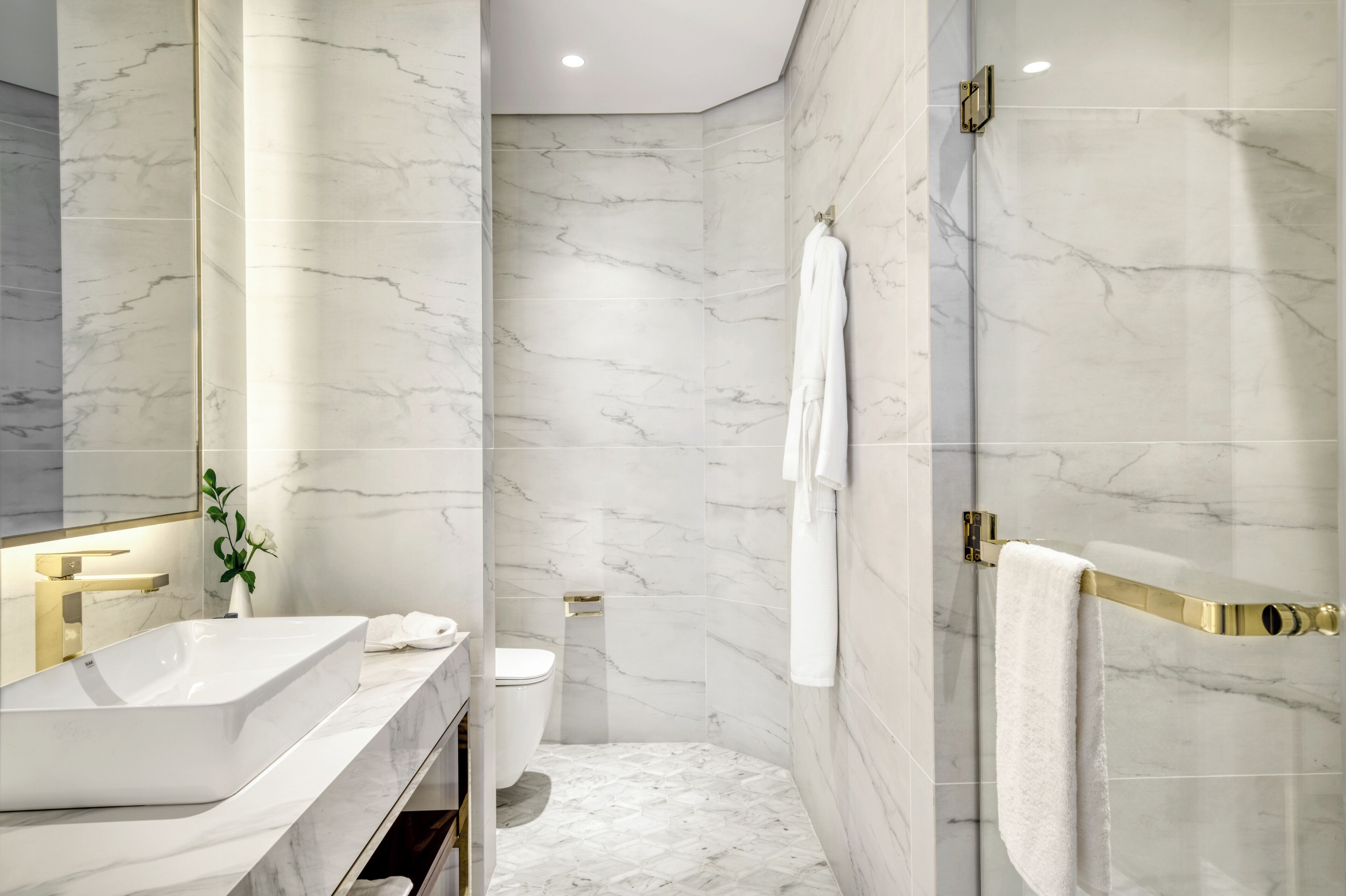 A modern bathroom with a marble sink, toilet, and shower area.