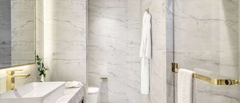 A modern bathroom with a marble sink, toilet, and shower area.
