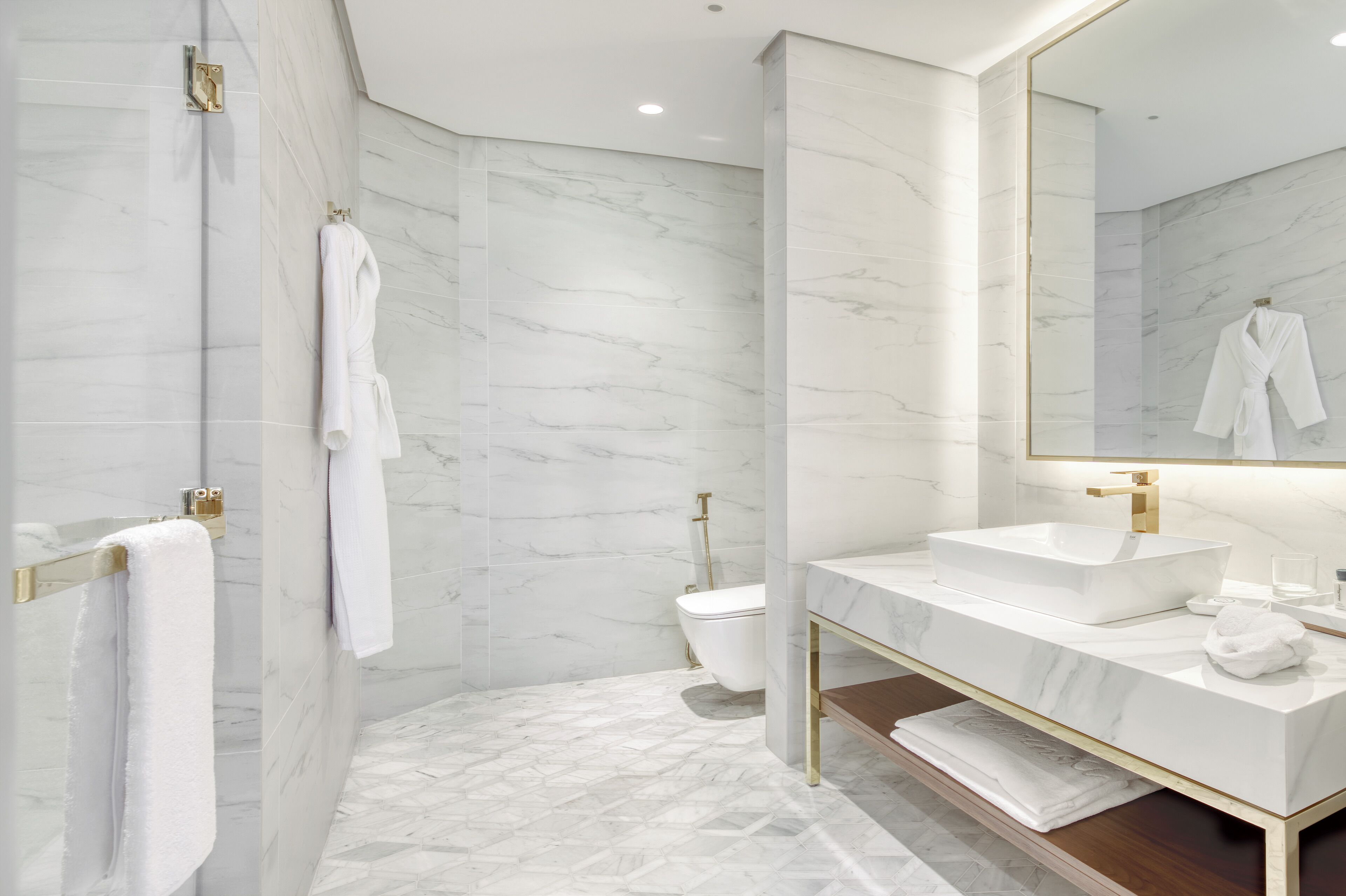 Un baño moderno con suelo de mármol, un lavamanos blanco y un espejo grande.
