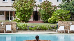 A swimming pool with lounge chairs and a building in the background. - Kyriad Nantes Sud Bouaye Aéroport (Bouaye)