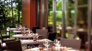 A restaurant with tables set for dining, featuring a view of greenery outside. - Kyriad Nantes Sud Bouaye Aéroport (Bouaye)
