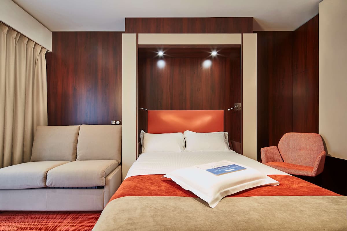 A hotel room with a bed, a sofa, and a chair.