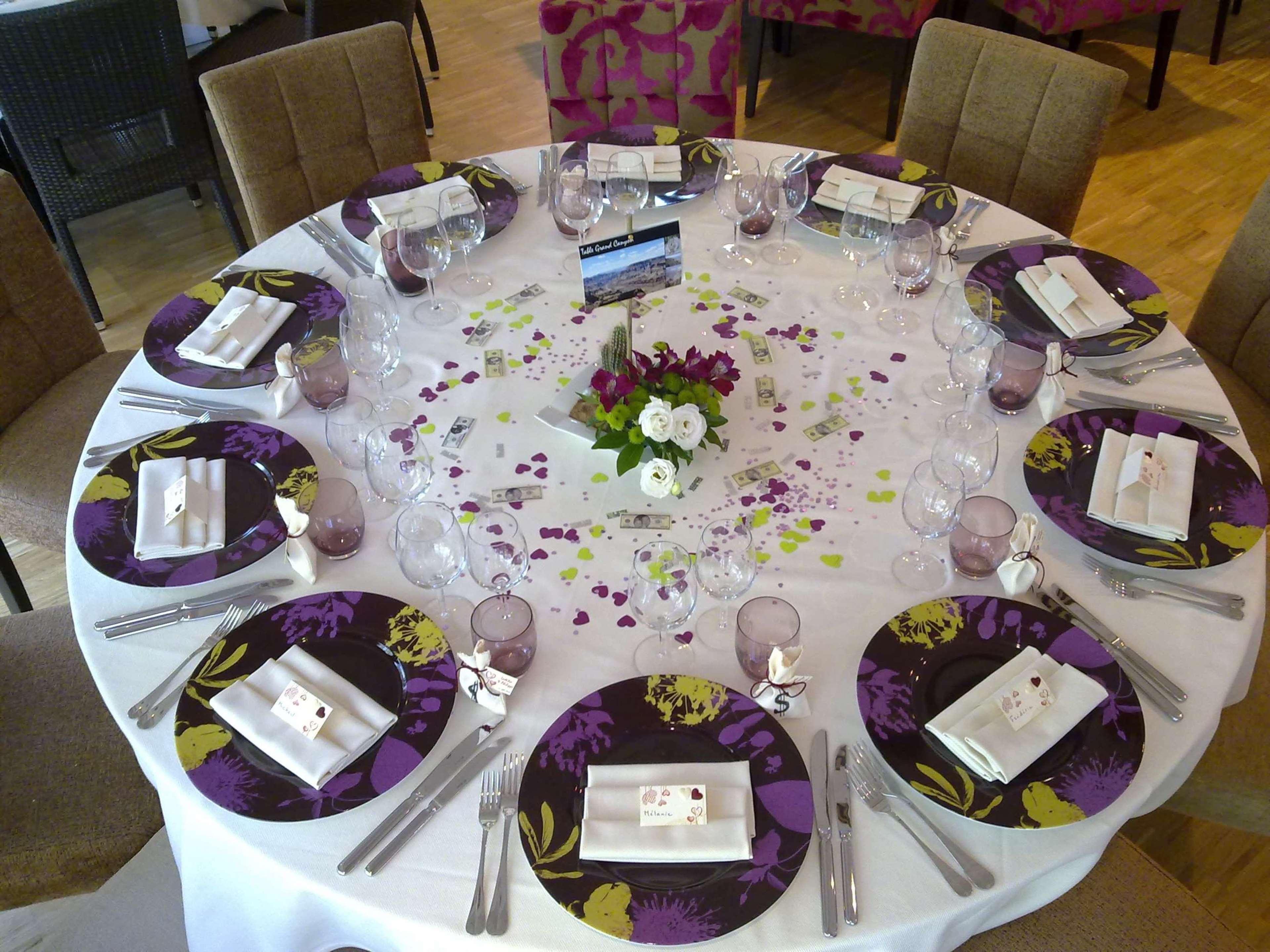 A round table set for a formal event with floral tablecloths, plates, cutlery, and glasses.