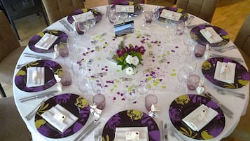 A round table set for a formal event with floral tablecloths, plates, cutlery, and glasses.