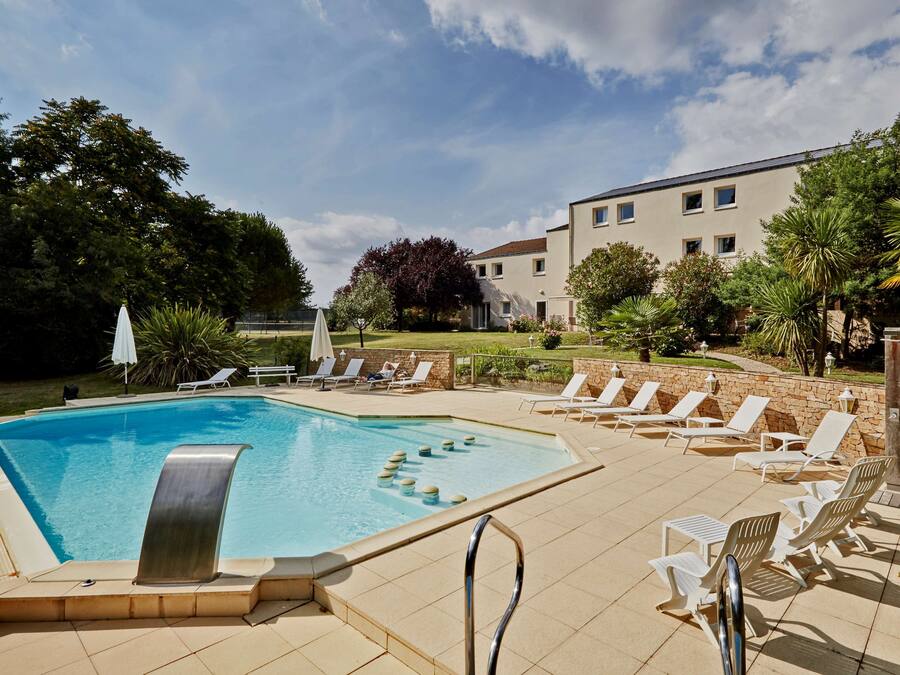 Une piscine avec des chaises longues et un mur en pierre.