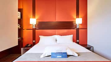 A hotel room with a large bed, two bedside lamps, a nightstand, and a telephone.