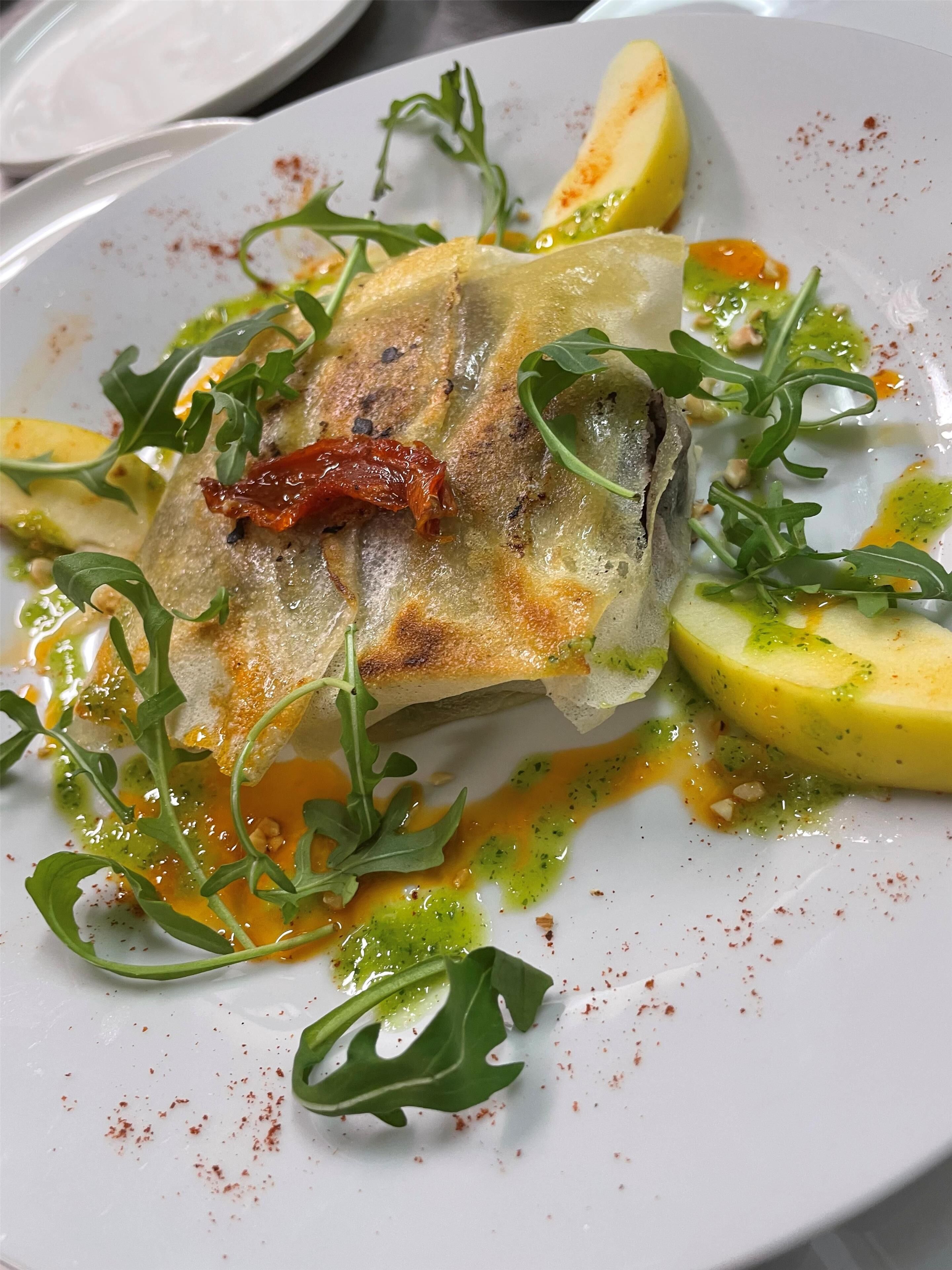 Une assiette de nourriture comprenant un morceau de poisson, des quartiers de citron et des légumes verts.
