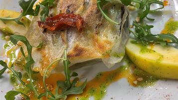 Une assiette de nourriture comprenant un morceau de poisson, des quartiers de citron et des légumes verts.