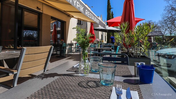 An outdoor seating area with tables, chairs, and umbrellas at Atypik Restaurant.