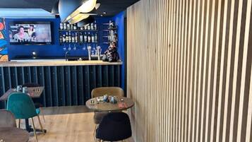 Ein Restaurantinneres mit Barbereich, einer Wand aus Holzleisten und runden Tischen.