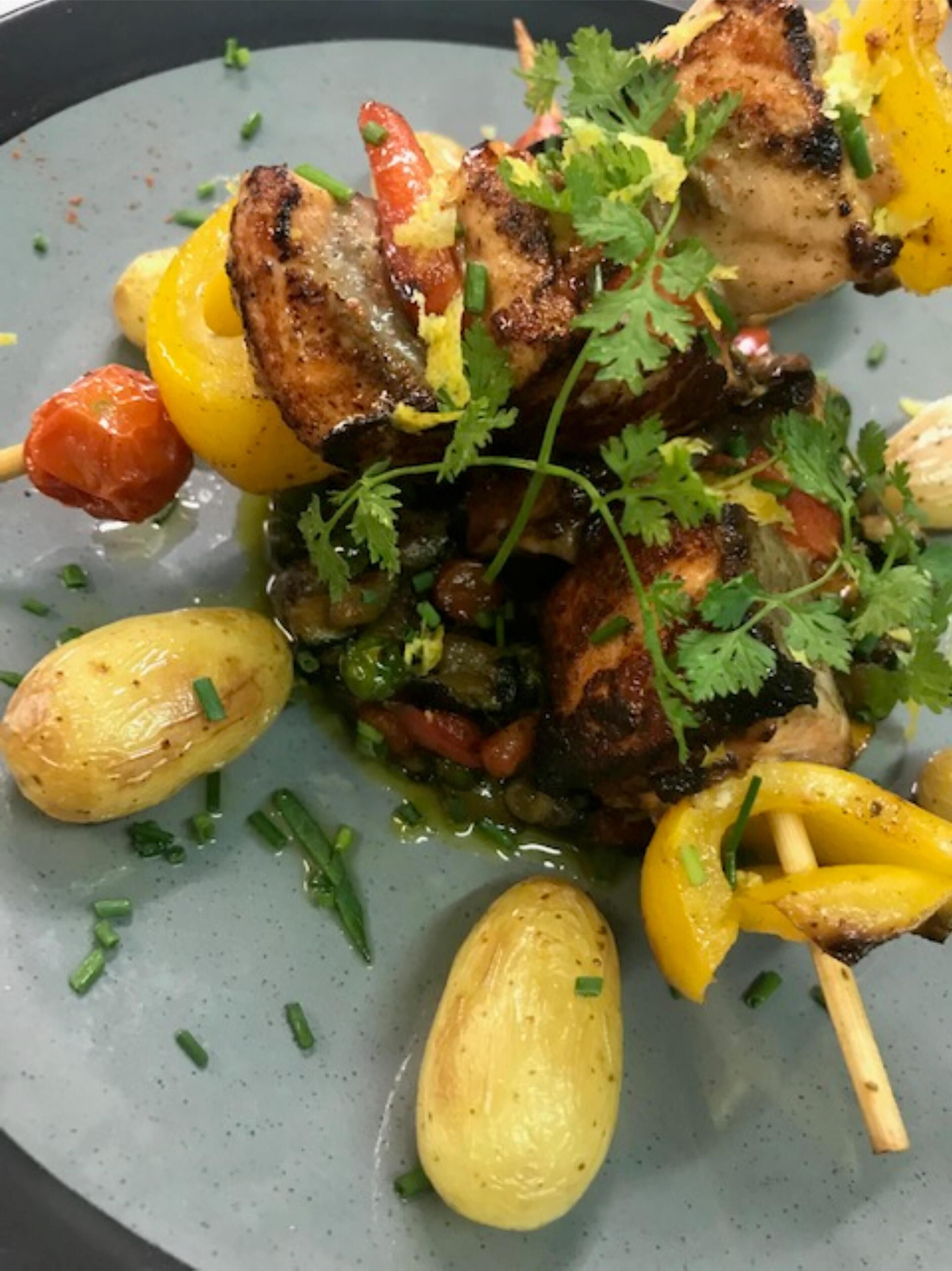 A dish with grilled chicken, vegetables, and herbs.