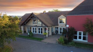 A two-story building with a sloped roof, large windows, and a well-maintained lawn.