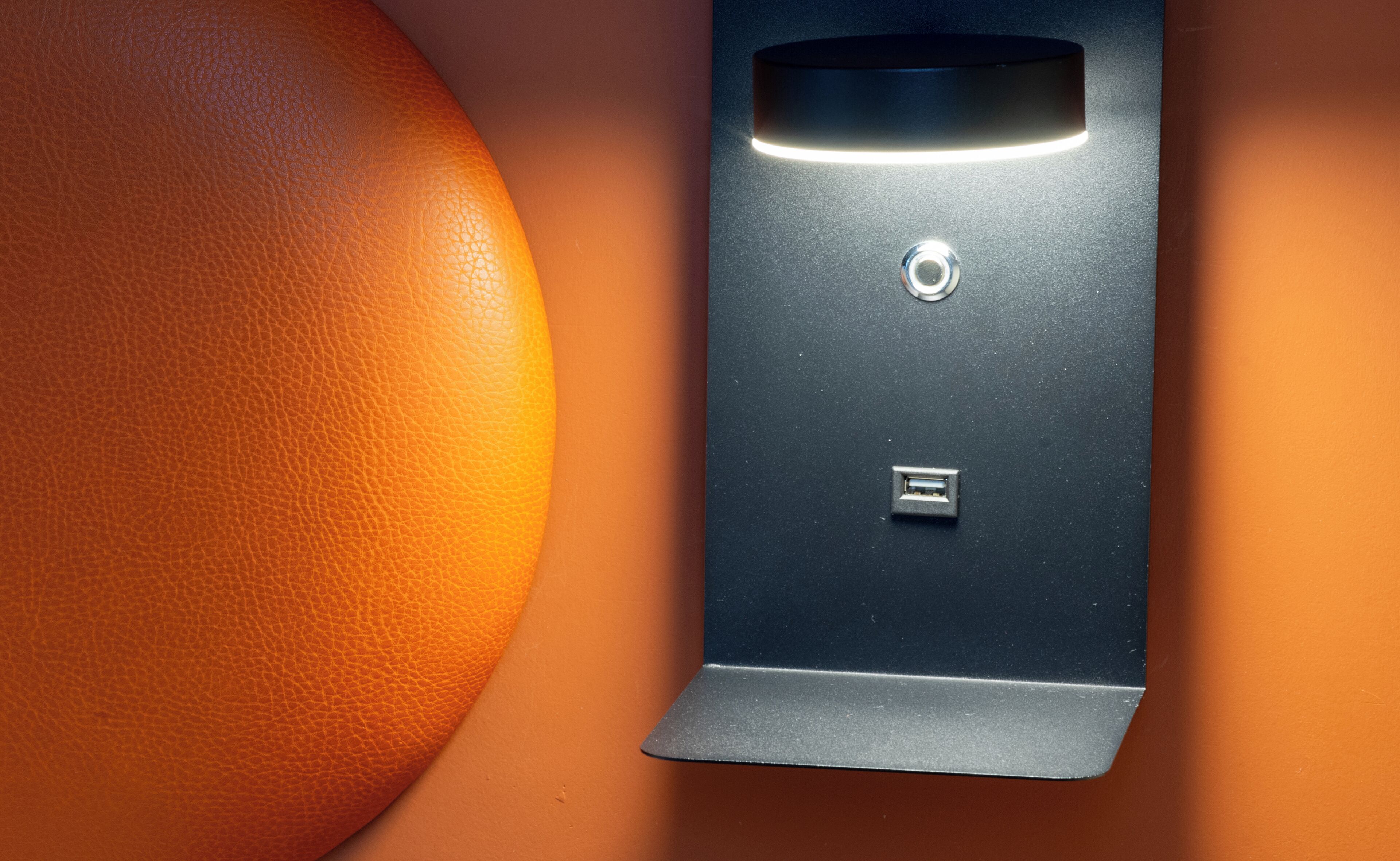 A metallic object with a rectangular shape, a circular button, and a rectangular slot, possibly a door handle or a control panel.