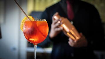 A cocktail in a glass with an orange slice, a straw, and ice cubes.