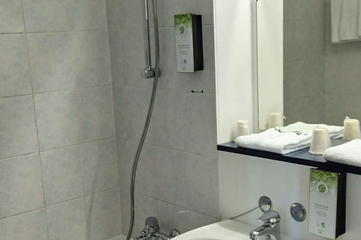 A modern bathroom with a bathtub, shower, and sink.