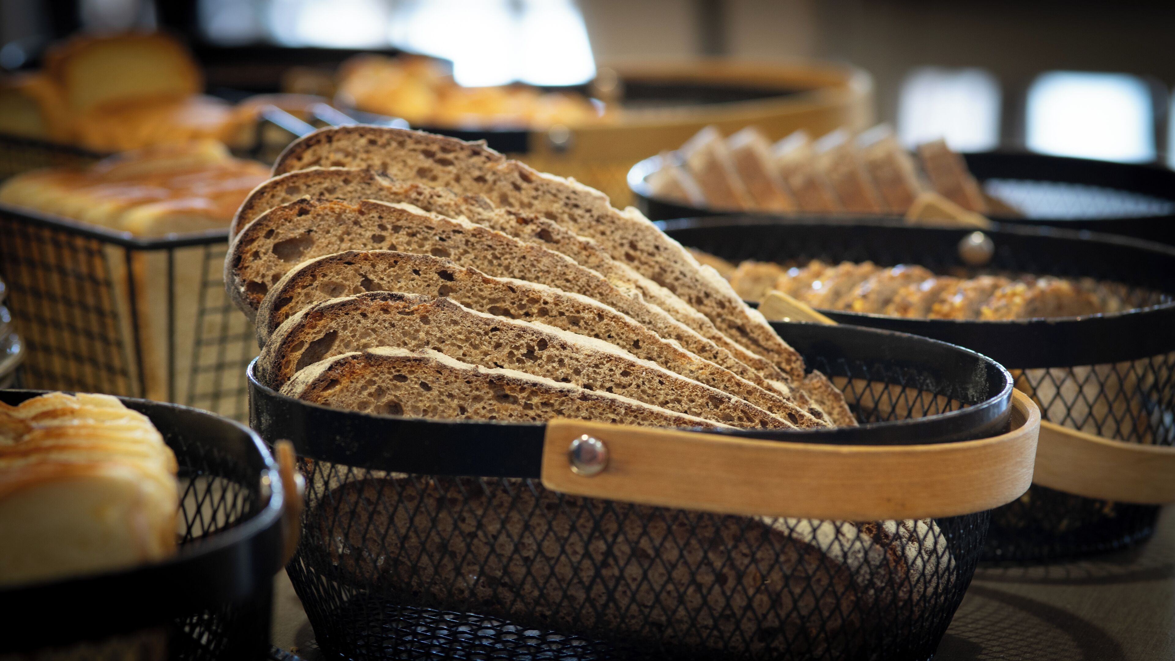 A variety of breads displayed in wire baskets.