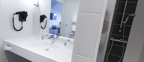 Uma casa de banho moderna com lavatório branco, espelho, telefone e zona de duche.