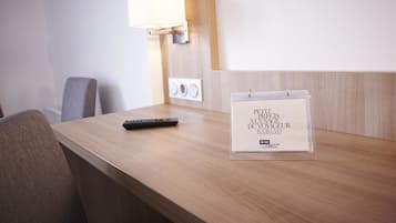 Un mostrador de recepción de hotel con un control remoto, un calendario y una lámpara de pared.