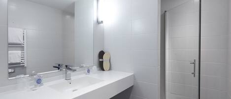 A modern bathroom with a white sink, a mirror, and a shower area.