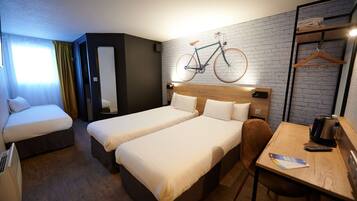 Habitación de hotel con dos camas, una mesa de madera, una bicicleta colgada en la pared y un perchero.