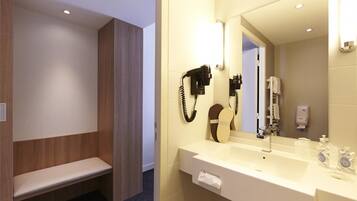 A modern bathroom with a bench, a hairdryer, and a mirror.