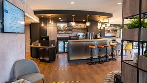 A modern bar area with a counter, stools, and a variety of bottles. - Kyriad Laval (Laval)