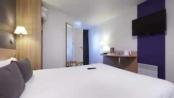 Een hotelkamer met een groot bed, een bureau met lamp, een flatscreen televisie en een spiegel.