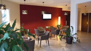 Ett modernt vardagsrum med en röd accentvägg, en platt-TV och flera sittgrupper.