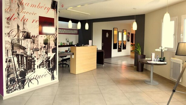 En modern hotellobby med en receptionsdisk, en sittgrupp och en stor väggmålning.