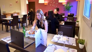 En restaurang med bord som är dukade för servering, där det finns datorer och menyer.