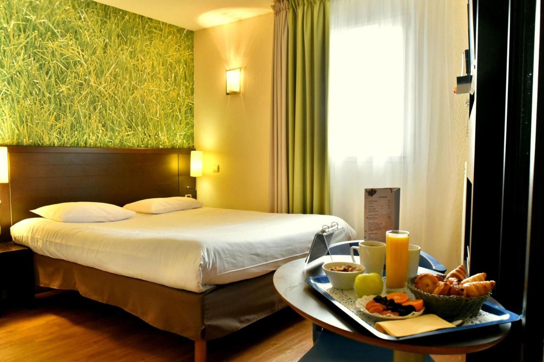 A hotel room with a bed, a breakfast tray, and a wall with a textured green design.